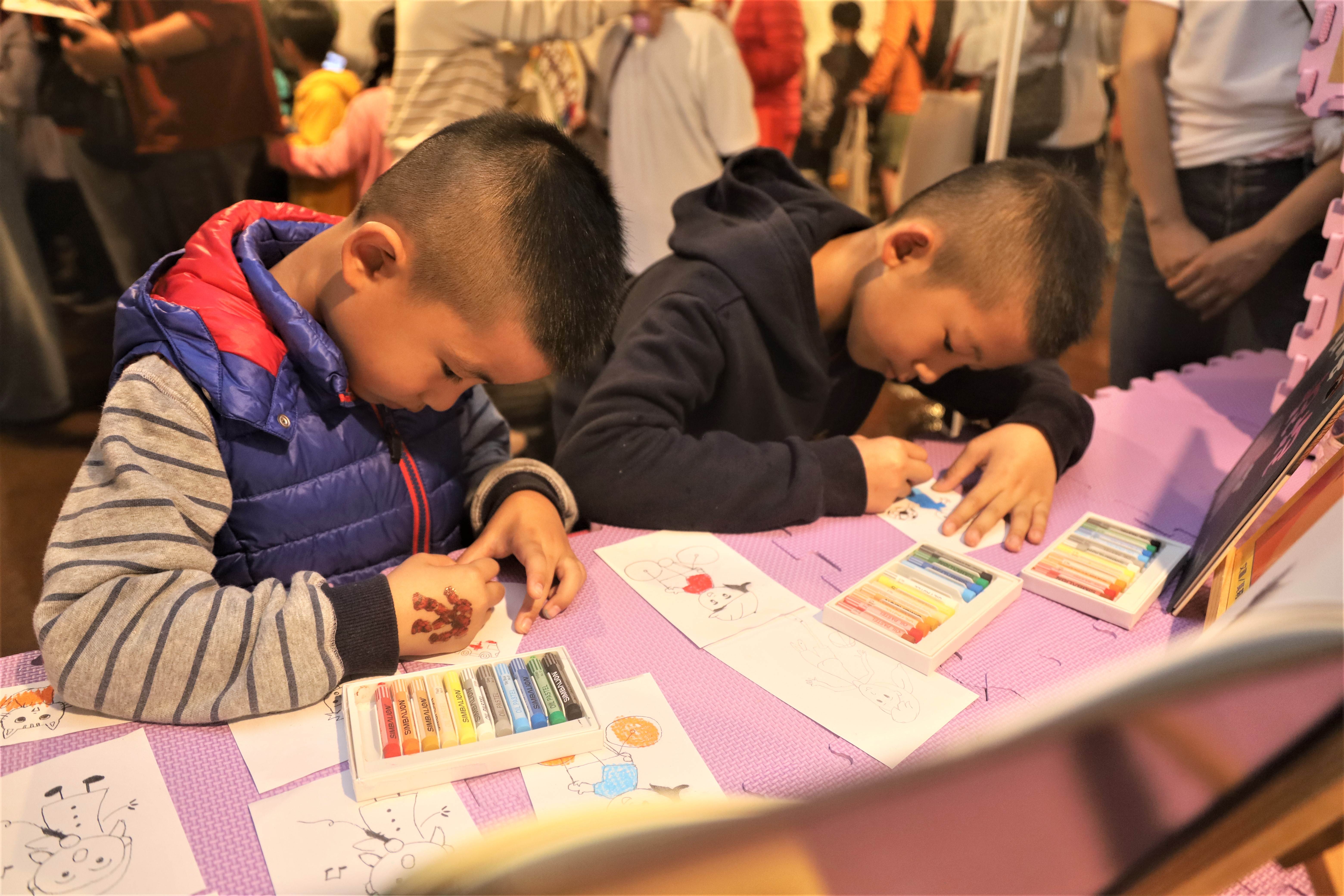 幼童專注於體驗攤位進行蠟筆繪圖