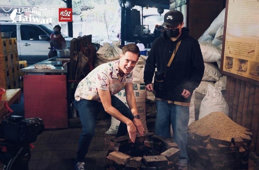 賈斯汀親手將新鮮食材小心地放入甕中，接著輕巧地鋪上稻穀，準備以傳統方式燜燒。每一步驟都充滿匠心，稻穀的香氣與食材的精華融合，為即將展開的燻製過程奠定了完美的基礎，讓人期待最終呈現的美味成果。（圖／Linking 368 Taiwan恁去台灣提供）