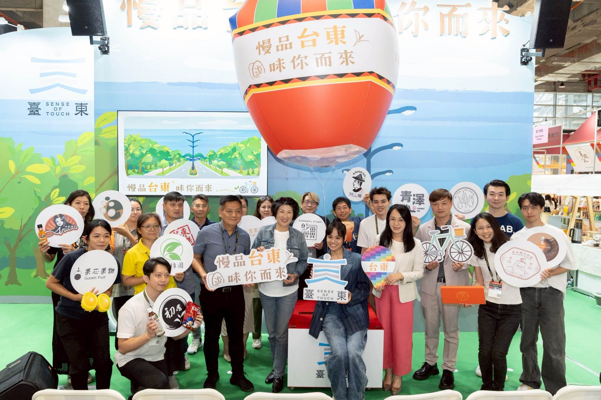 臺東館開幕合影 展現<a href='/search/tags/慢食生活/' target='_blank'>慢食生活</a>美學，饒慶鈴縣長（前排中）偕同立委陳瑩、臺東創作歌手郭芝吟（吱吱）及多位參展業者共同為臺東館揭幕，以熱氣球造型呼應臺東特色，邀請大家一同「慢品臺東 味你而來」。（圖／臺東縣政府提供）