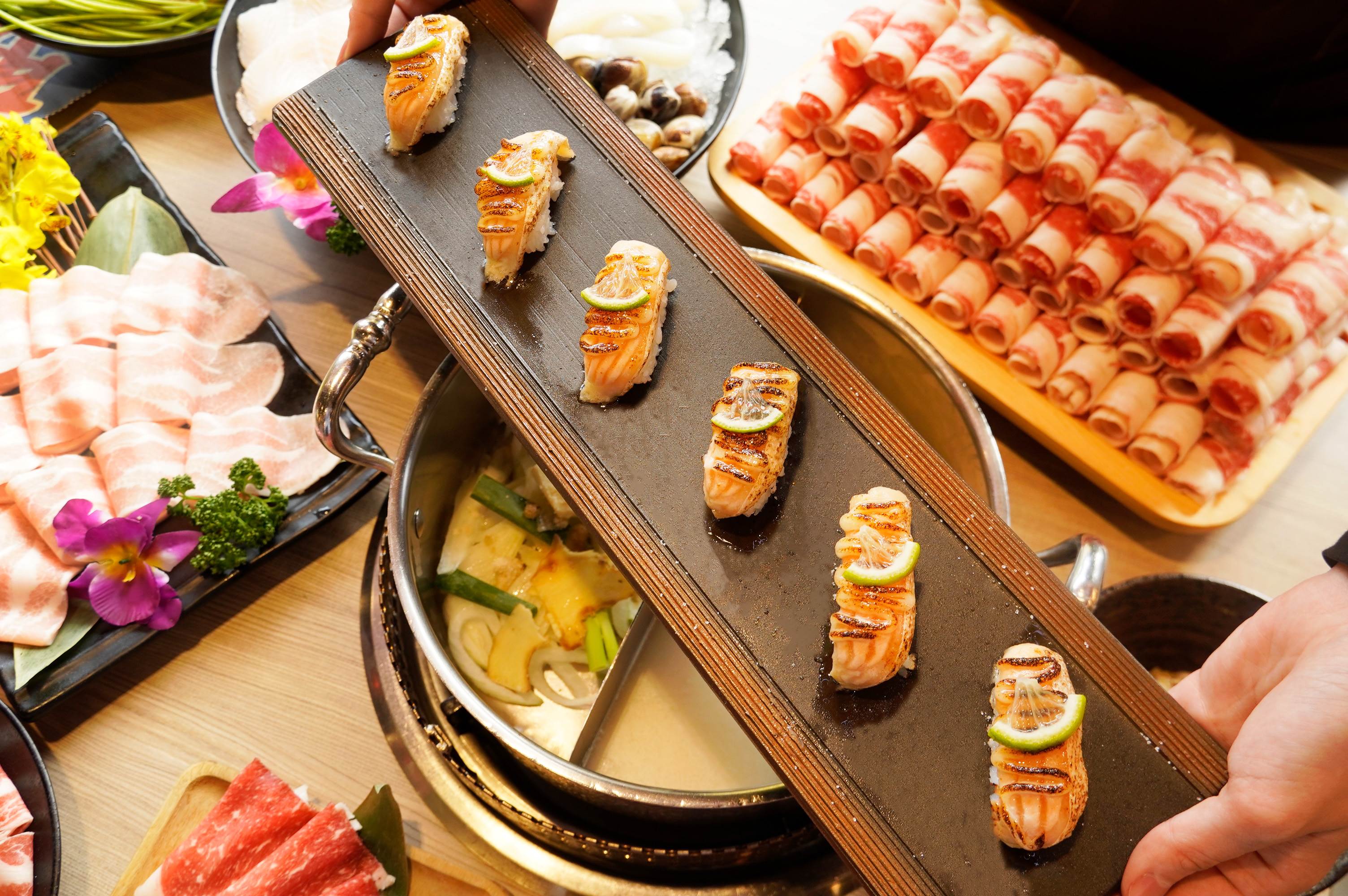 除了美澳雙和牛、漁港直送海鮮與百種火鍋料無限供應，還能享用「職人炙燒焦糖鮭魚握壽司」吃到飽。（圖／馬辣集團提供）