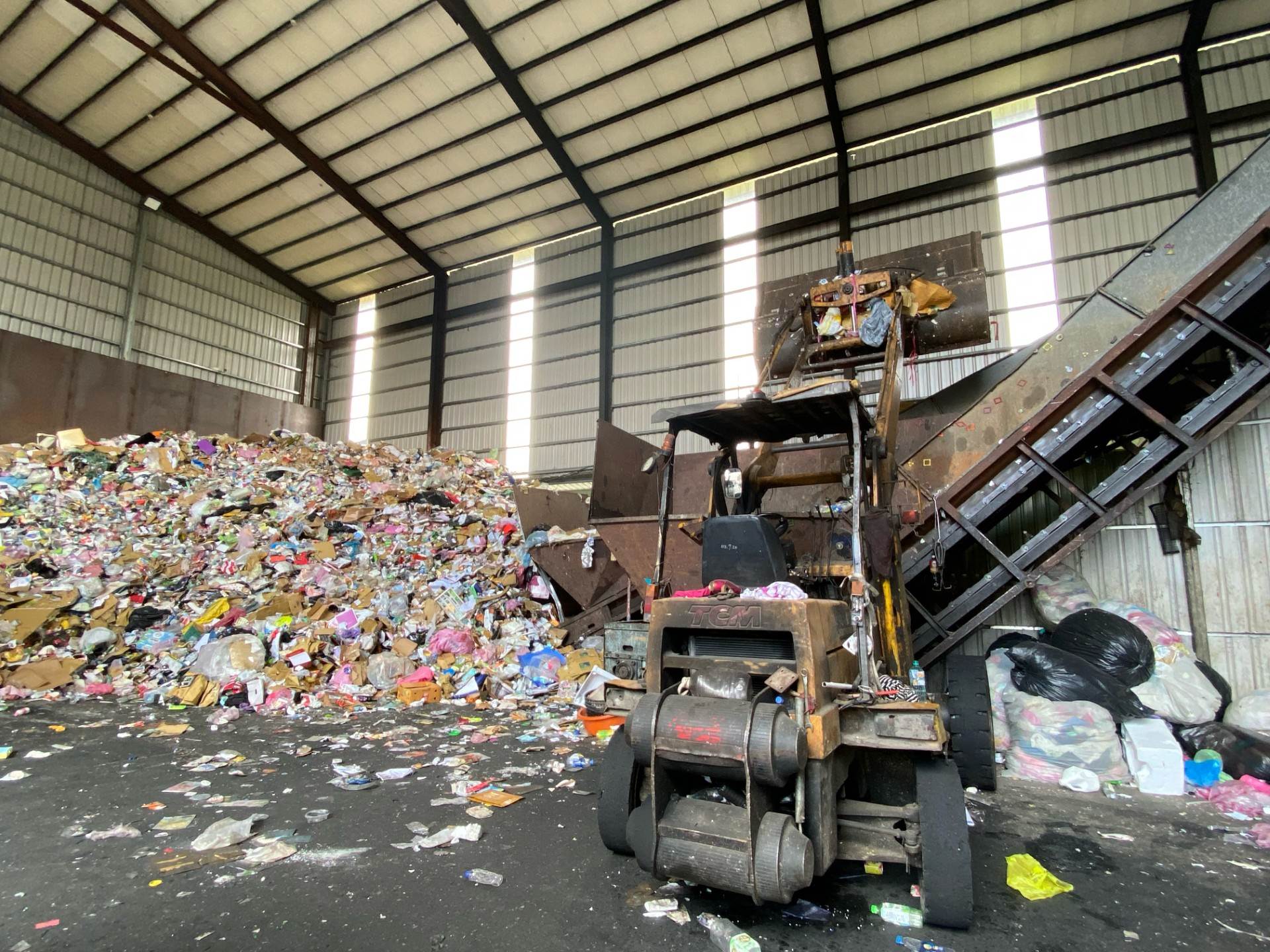 圖1、回收場內堆滿壓縮紙箱與寶特瓶山,空氣悶臭、垃圾散落一地