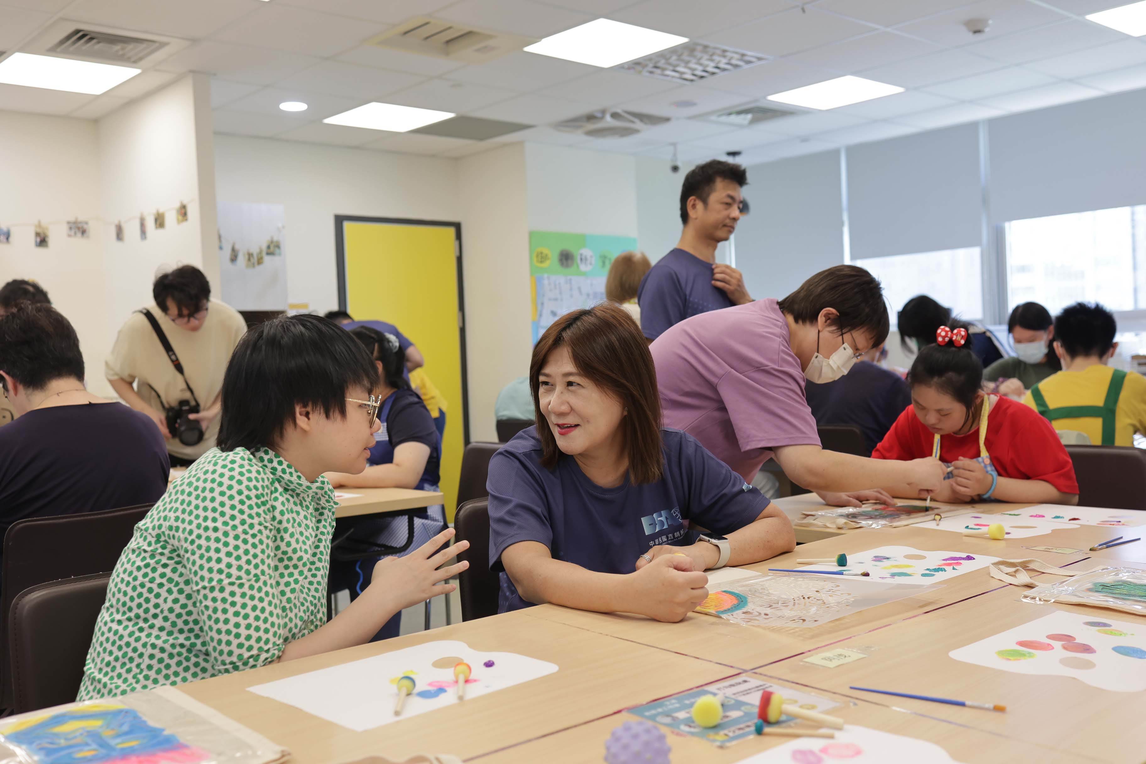 直銷協會理事長蔡孟紅，現場與憨兒交流，聊談彼此興趣愛好。（圖／直銷協會提供）
