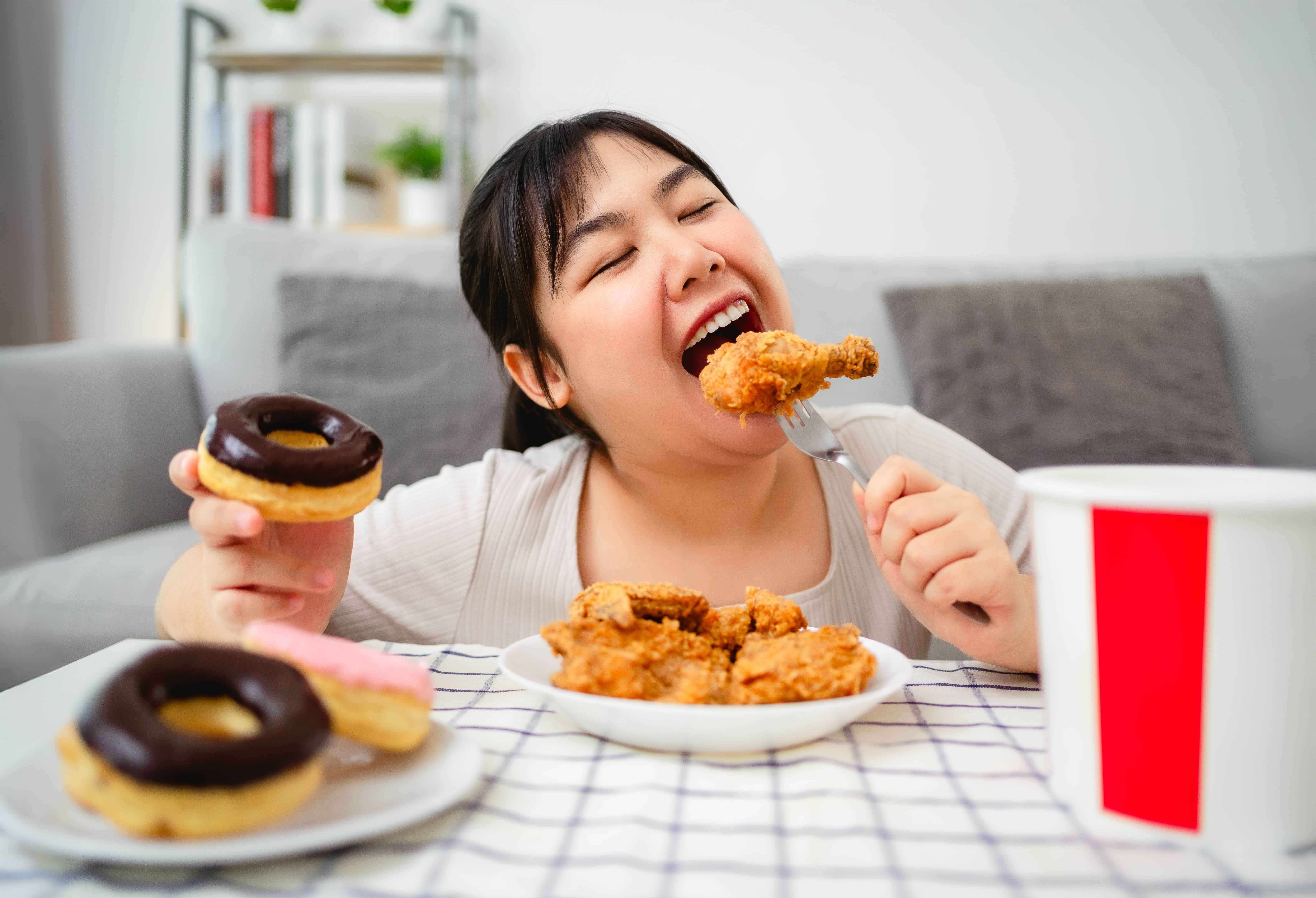 woman-is-happily-eating-fried-chicken-donuts-plate-fast-food-unhealthy-food-concept (2)