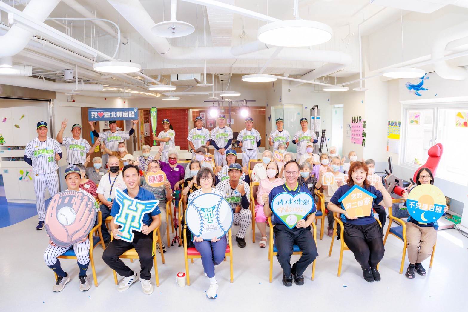 臺北市政府體育局黃力卉專門委員、一粒麥子社福基金會林木泉執行長、台北服務中心趙甄琳主任、王佳慧機構長、臺北市政府體育局競技運動科李俊義科長、一粒麥子基金會莒光社區長照機構長輩及臺北興富發棒球隊隊員合照