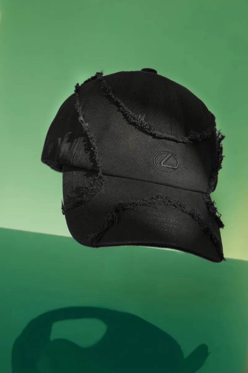 「解構鬚邊鴨舌帽」前衛的鬚邊細節呼應Lexus Spindle Grille紡錘型水箱護罩設計，後方紅色符號象徵能量核心。（圖／HOTAI購官網）