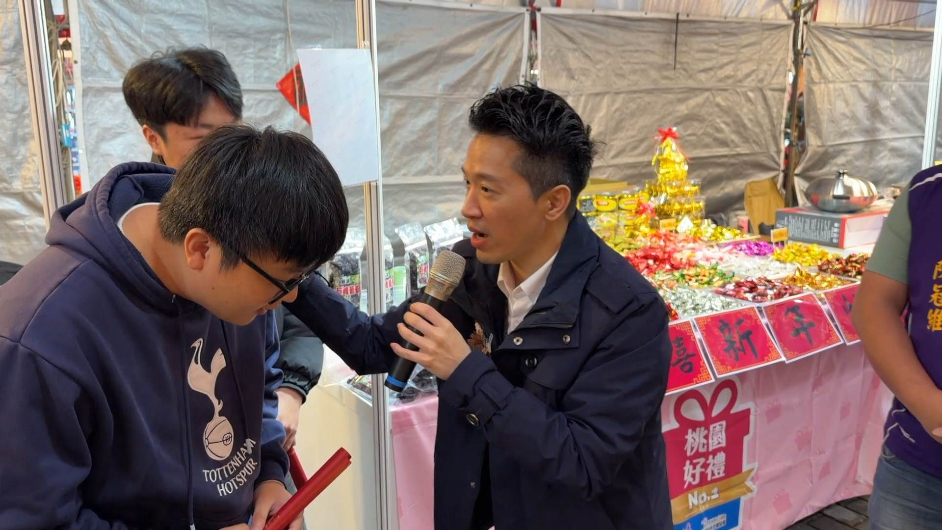  何志偉逐攤向攤商拜早年、發送春聯。（圖／東森新聞）