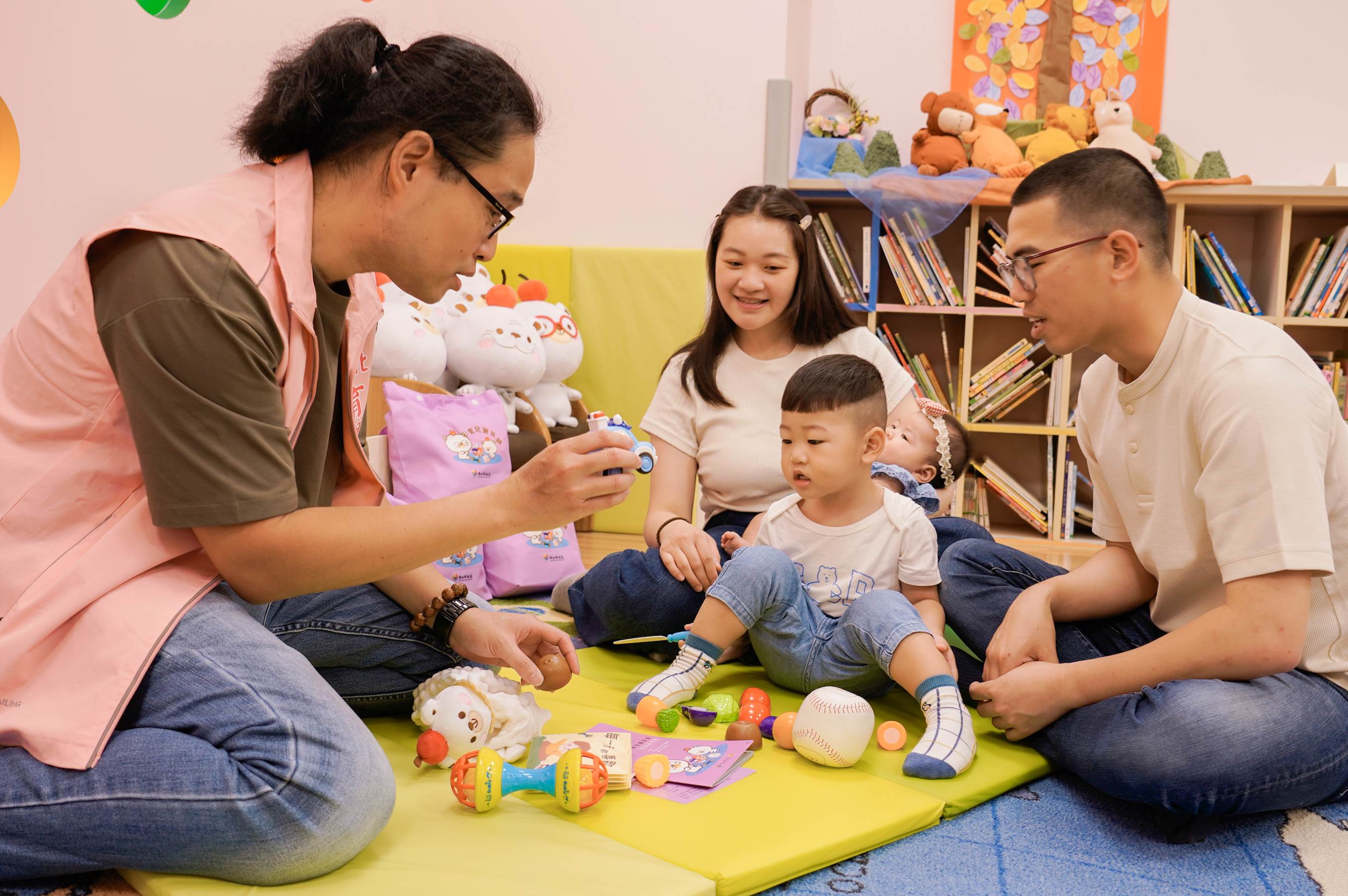 新北市設置幼兒指導員（左1），可以協助新生兒父母育兒指導，利用寶貝袋裡面的內容物來跟孩子進行發展篩檢。（圖／新北市政府社會局提供）