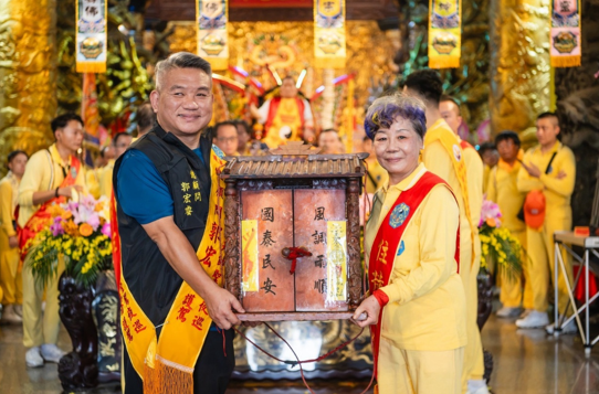 桃園護國宮總顧問郭宏睿與住持夫人張雪娥參與「萬人傳香」，共同傳遞香擔。（圖／陳乃瑋攝影、桃園護國宮提供）